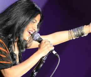 Image of singer Falu holding microphone singing with purple background