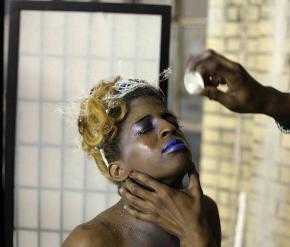 Krystal, a dark skinned woman, hold hers face up as an arm reaches out and sprinkles her with glitter