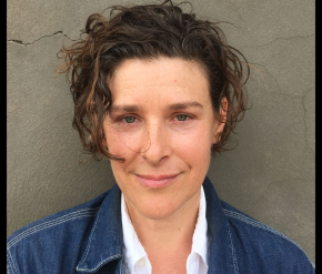 A woman in a denim jacket with short hair smiling