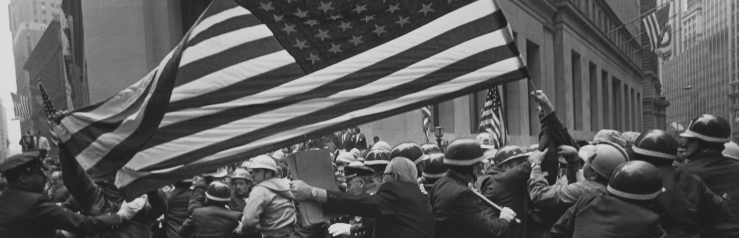 A crowd of protesters at a Pro-Vietnam-War demonstration holding a large American flag