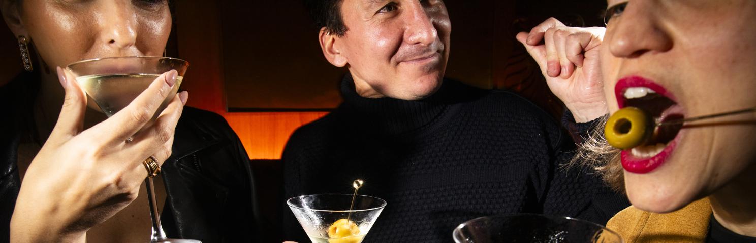 Three people drinking martinis with olives
