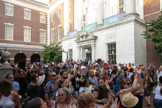 A large group of people dance outside of a museum. 