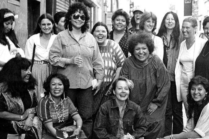 Photograph of artists from the exhibition, Women of Sweetgrass, Cedar and Sage, friends and community members outside the American Indian Community House Gallery taken in 1985.