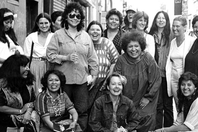 Fotografía de artistas de la exposición, Women of Sweetgrass, Cedar and Sage, amigas y miembros de la comunidad fuera de la American Indian Community House Gallery tomada en 1985.