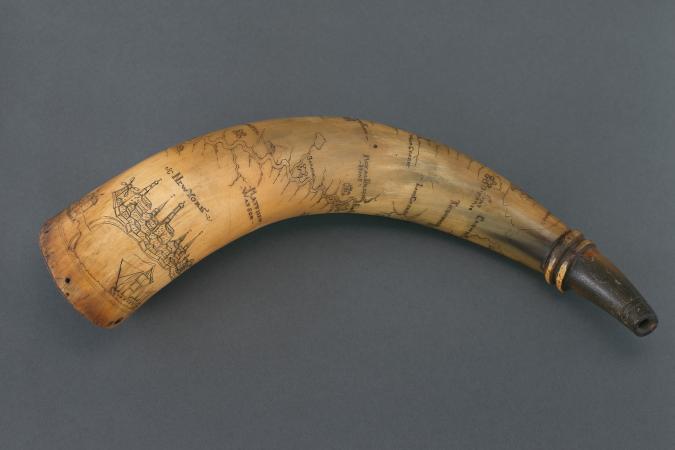 An engraved horn against a gray background. 