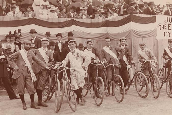 Os homens se alinham com suas bicicletas enquanto os espectadores observam de assentos elevados antes do The Evening Telegram Bicycle Parade