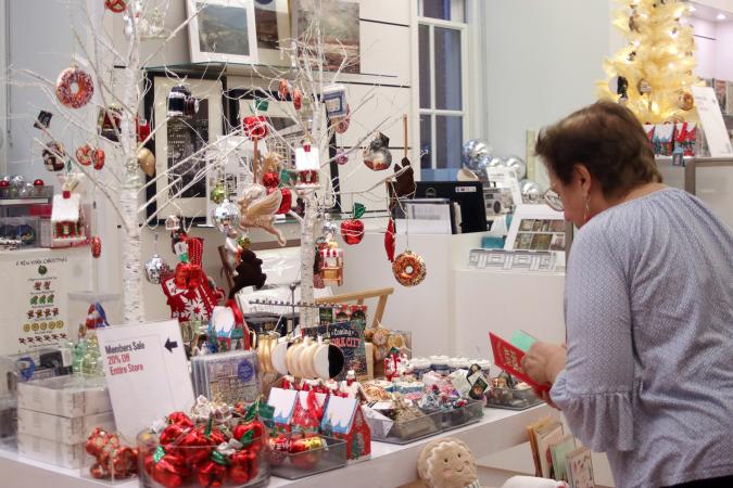 A woman browsing holiday-themed items in the MCNY shop