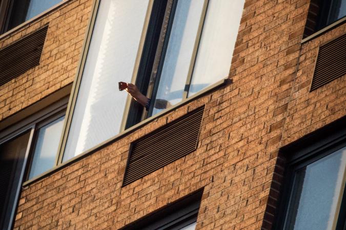 Alguém segura um badalo do lado de fora da janela de um apartamento como parte da "saudação das 7h" durante a pandemia de COVID-19.