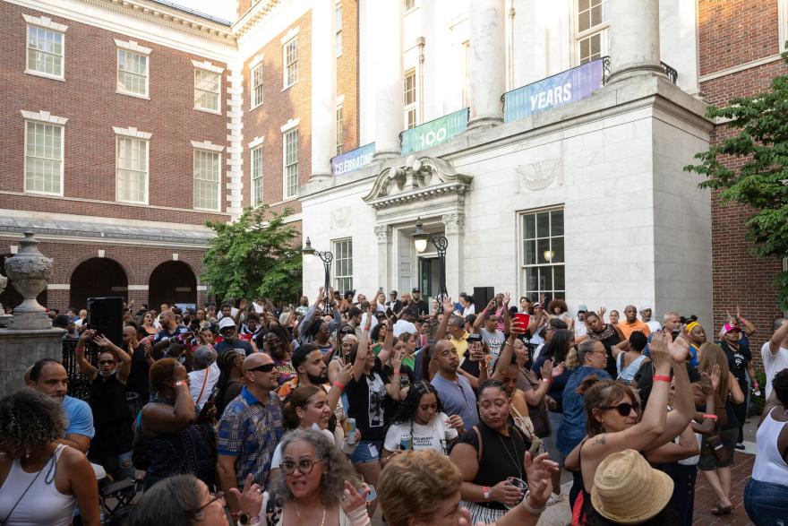 A large group of people dance outside of a museum.