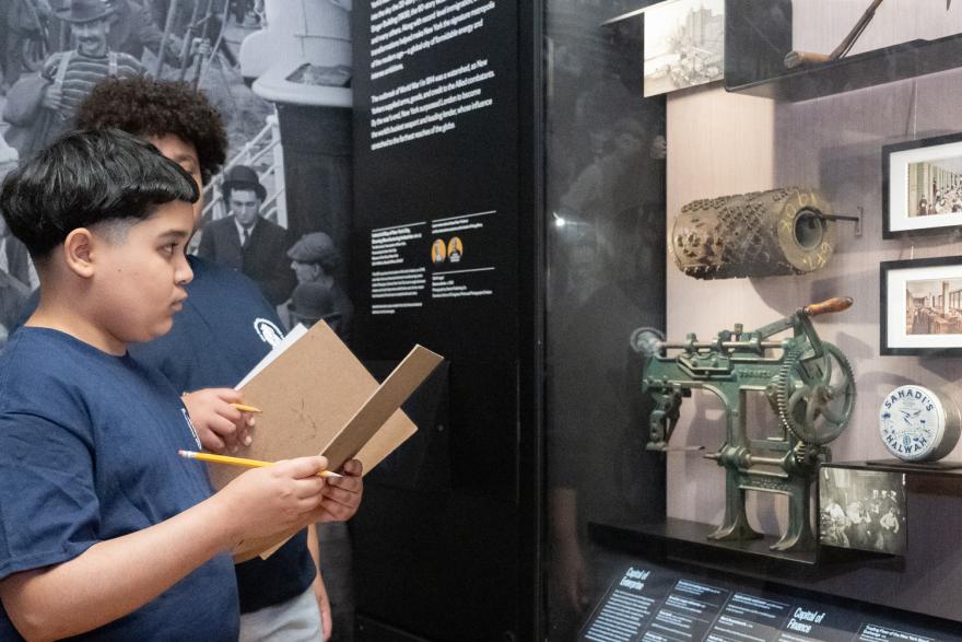 A group of three students examining collection objects in a display case.