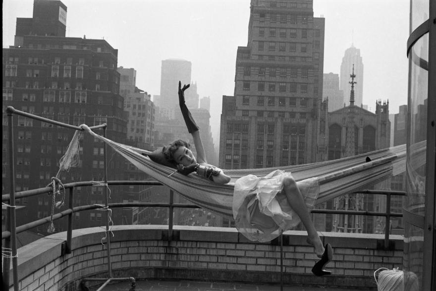 Woman laying in a hammock on a roof with the city skyline in the background 