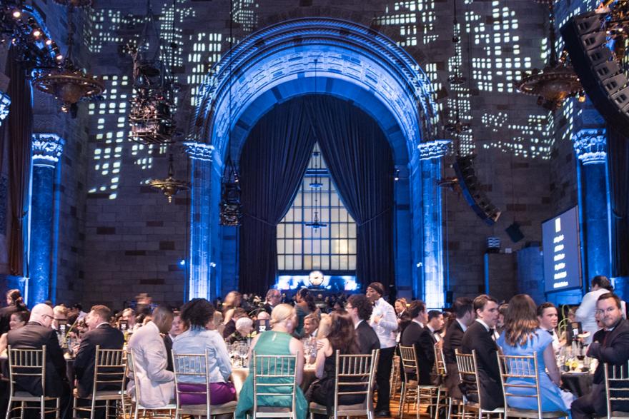 A crowd of people sitting beneath a projection of a city skyline