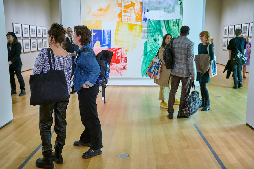 A group of visitors inside of a gallery with colorful works on the walls
