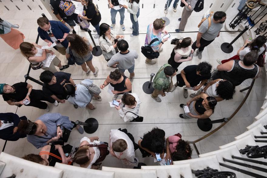 A crowd of visitors beneath a marble spiral staircase.