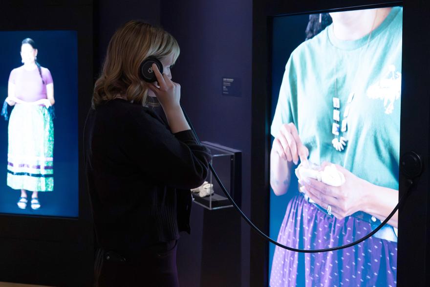 A person listens to audio at an interactive screen in a gallery