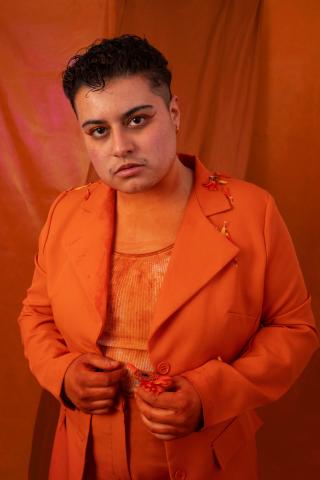 Une personne en costume orange pose devant la caméra.
