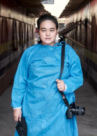 A woman stands with a camera. 