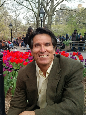 Fotografía de Rick Chavolla en un parque público sentado o arrodillado frente a un grupo de tulipanes rojos y morados