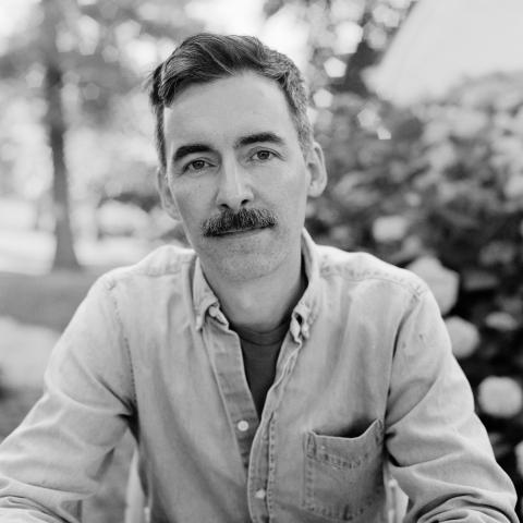 Black and White photo of a man as he looks into the camera. 