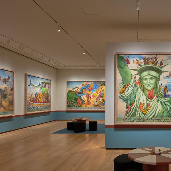 Large mural panels showing Alice and other characters exploring New York City, with red and white tables in the middle of the gallery.