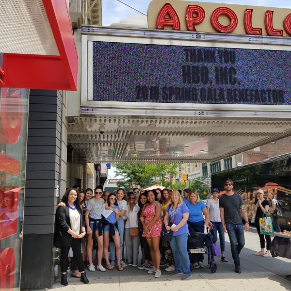 Un groupe de touristes debout sous le chapiteau de l'Apollo Theatre