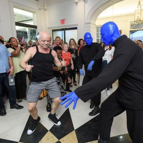 Three Blue Men (from Blue Man Group) dance in the Museum Lobby with visitors during Uptown Bounce in August, 2019.