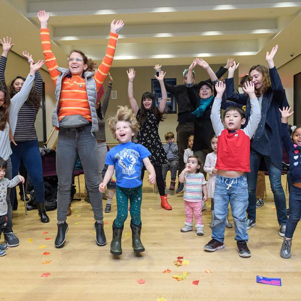 A group of adults and children jump. 