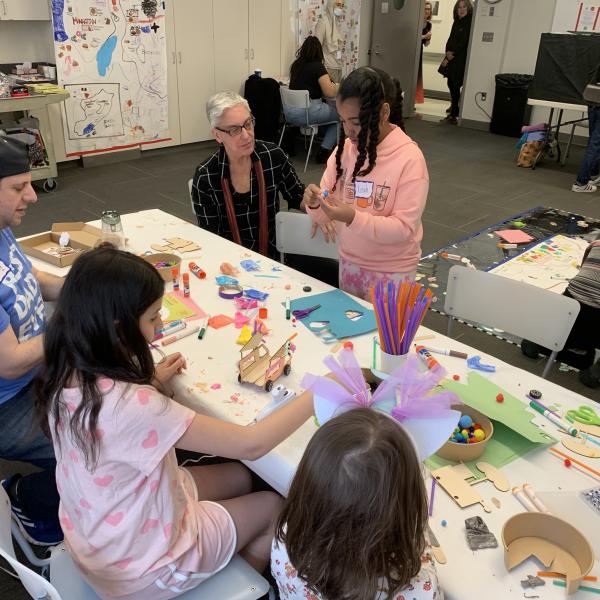 An image of families sitting around a table and working on a shared project