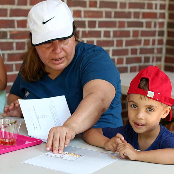 Photograph of a family participating in a wet water lab, involving the testing varying pH levels of different liquids. 