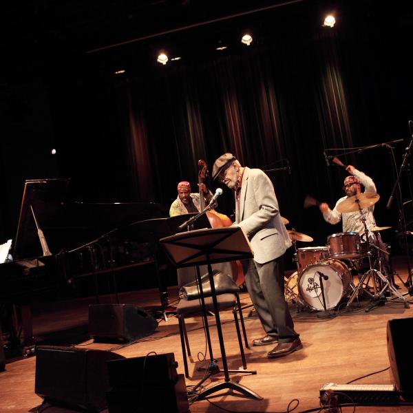 El poeta Amiri Baraka actuando con un grupo de músicos de jazz en un escenario.