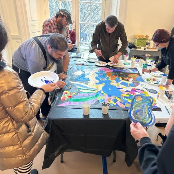 Manny Vega and visitors paint a mermaid portrait together. 