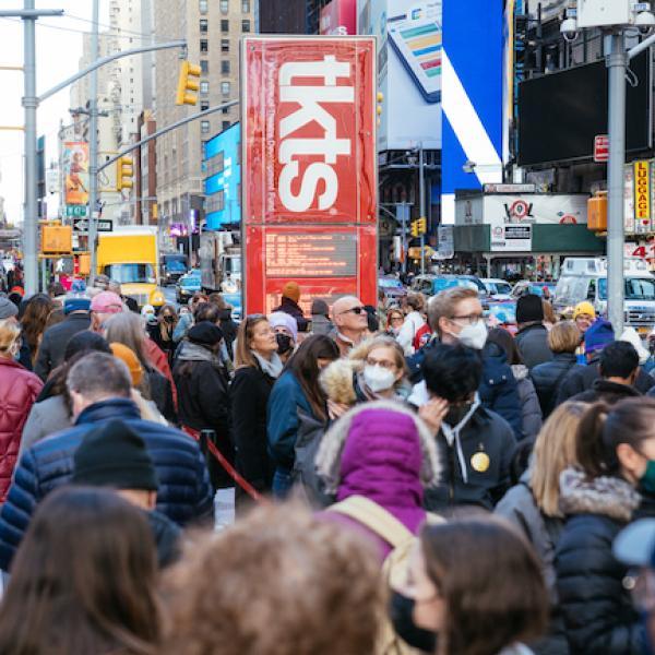 Photograph of crowds walking around Times Square, the tkts kiosk is visible in the center of the image.