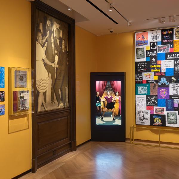 Museum exhibition with yellow walls and people dancing 