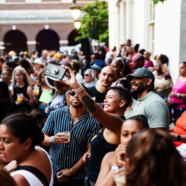 A crowd of people outside of the Museum of the City of New York and four people taking a selfie.