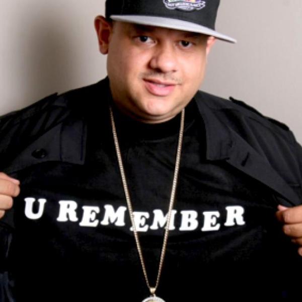 Dj ted smooth smiles at the camera wearing a shirt that says "U REMEMBER."