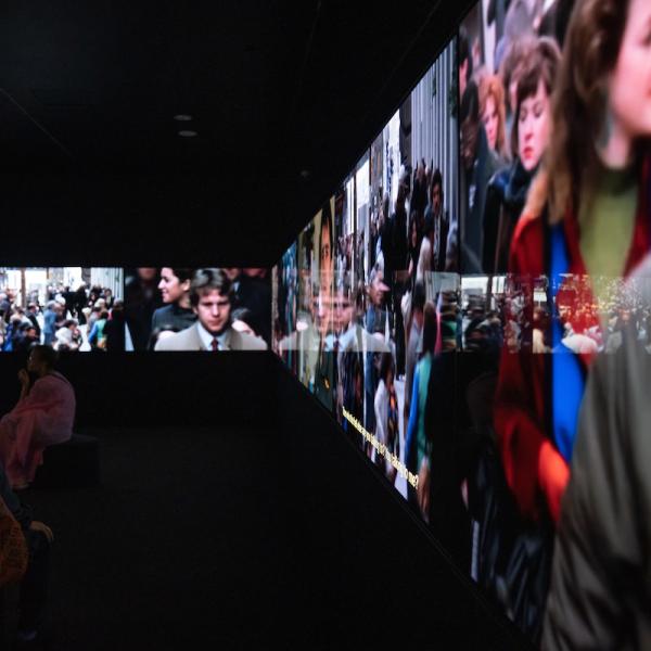 Vue de l'installation de You Are Here montrant diverses séquences vidéo diffusées sur une section du film immersif de 16 écrans