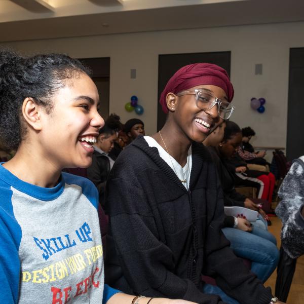 Three teenagers laugh together. 