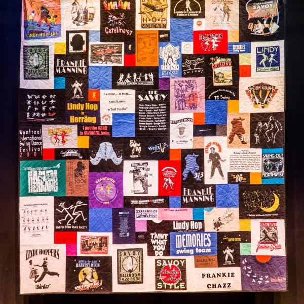 An image of a quilt with multiple colorful rectangular patches with people dancing and words like "Frankie Manning" and "Savoy"