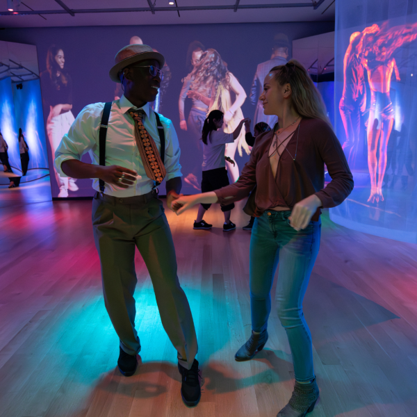A man and woman smiling and dancing together on a disco dance floor