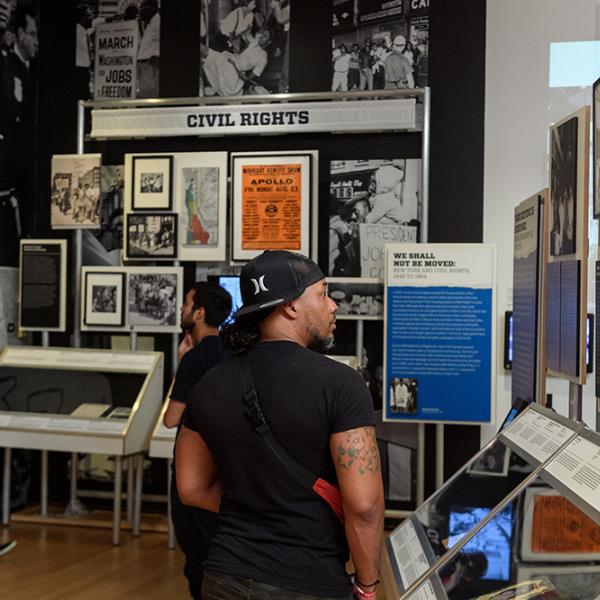 Um visitante da exposição Ativista Nova York do Museu da Cidade de Nova York examina artefatos sobre a história da mudança social na cidade.