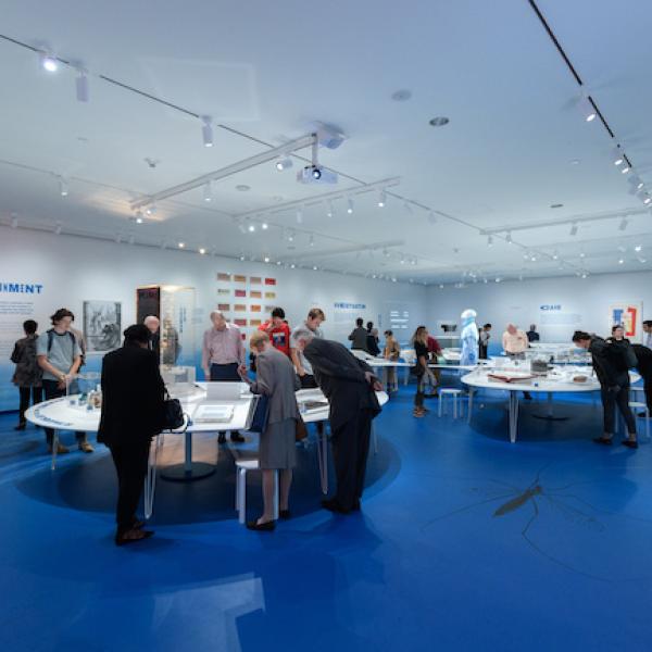 Installation Shot of Germ City: Microbes and the Metropolis, with a crowd looking at the exhibition.