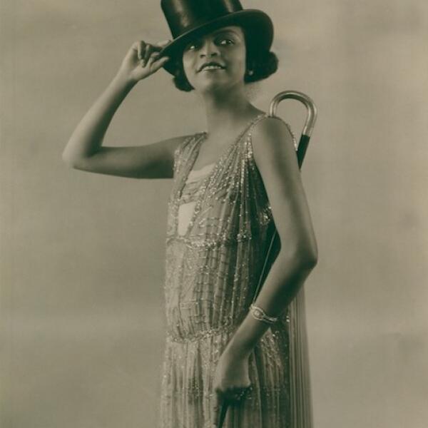 Une photographie en noir et blanc de Florence Mills posée dans une robe de fantaisie avec chapeau haut de forme et canne