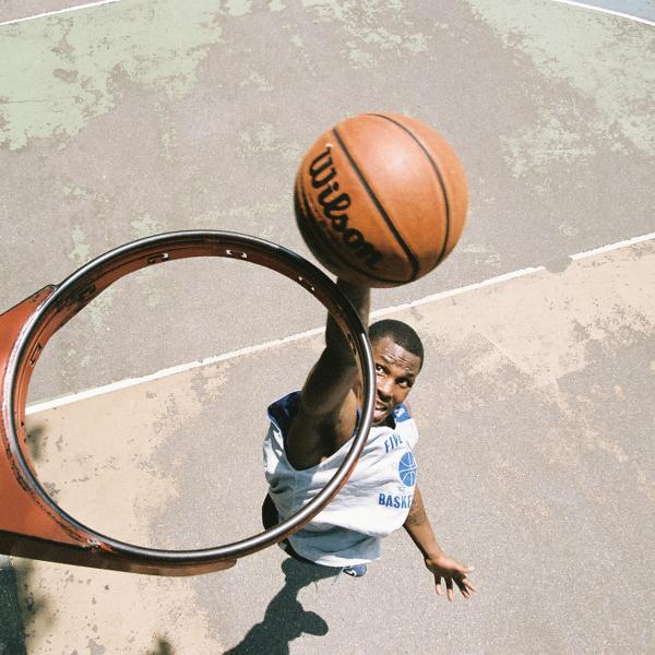 Vue de dessus d'un panier de basket sans filet, où un joueur est vu sur le point de plonger un ballon de basket à travers le panier