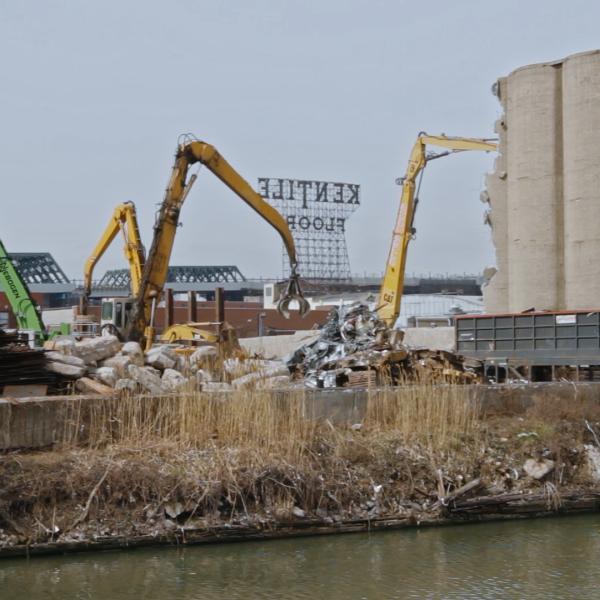 Excavators moving concrete in front of water 