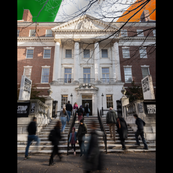 Visitors walking up the front steps of the Museum of the City of New York with flag of Ireland in background.