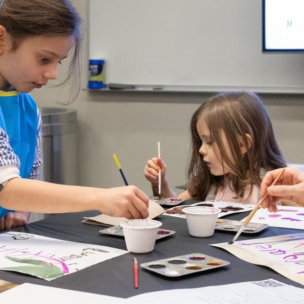 Two children creating an artwork with watercolor paint.