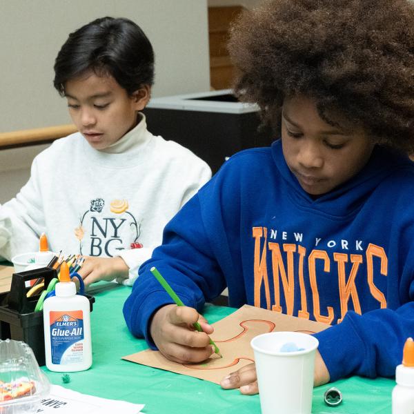 Two children creating an artwork with colored pencils.