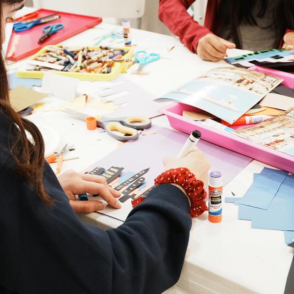 Two children creating an artwork with glue and cut paper.