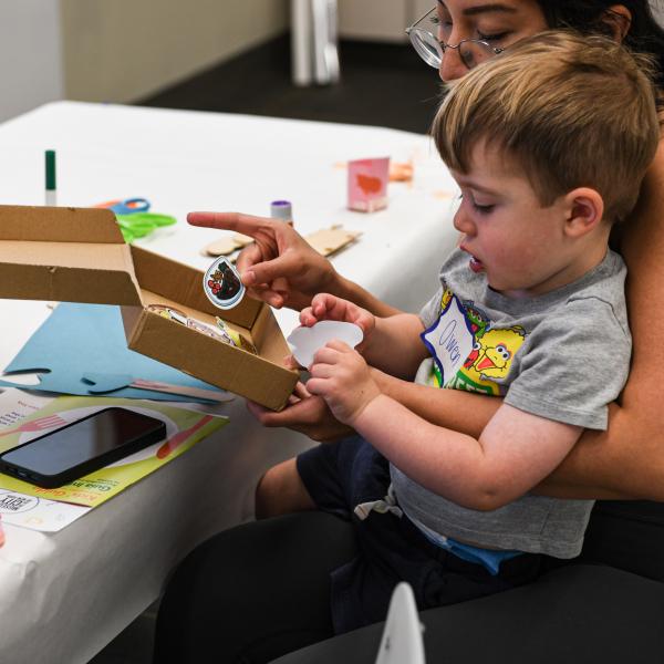 A woman helps a small child with an art project. 