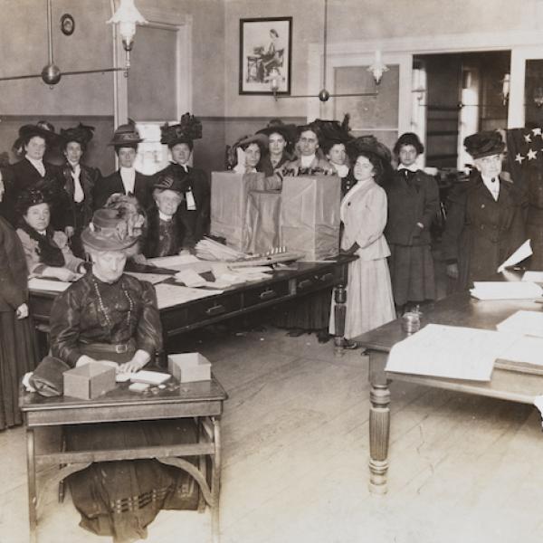 Women voting, likely just after women's suffrage was legalized. Poster in the corner reads "Women vote for president".